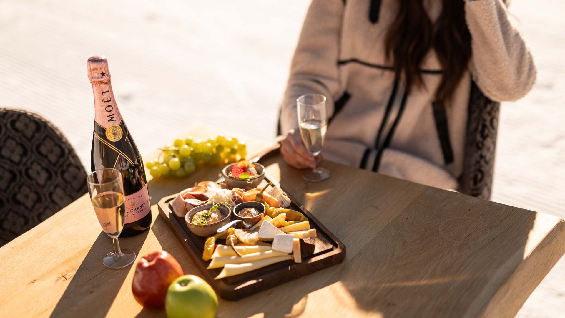 Frau sitzt draußen mit einer Essensplatte und Champagner Frau sitzt draußen mit einer Essensplatte und Champagner