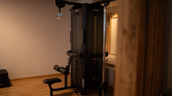 Fieberbrunn: wellness hotel wanted? Black strength training machine in gym with wooden floor and plain walls