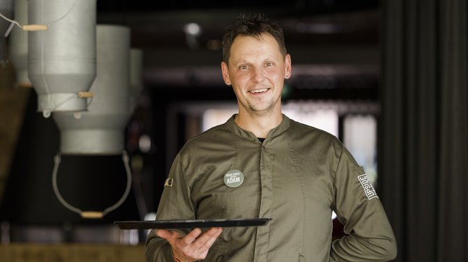 Team der ADEA Lifestyle Suites Fieberbrunn Lächelnder Kellner mit Tablett in einem Restaurant