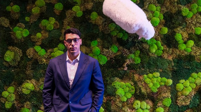 Team der ADEA Lifestyle Suites Fieberbrunn Mann im Anzug vor einer Wand mit grünem Moos und einem weißen Mikrofon