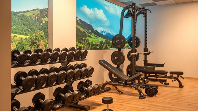 ADEA: dein Hotel mit Fitnessstudio in Österreich Fitnessstudio mit Hanteln, Gewichtheberbank und Berglandschaft an der Wand