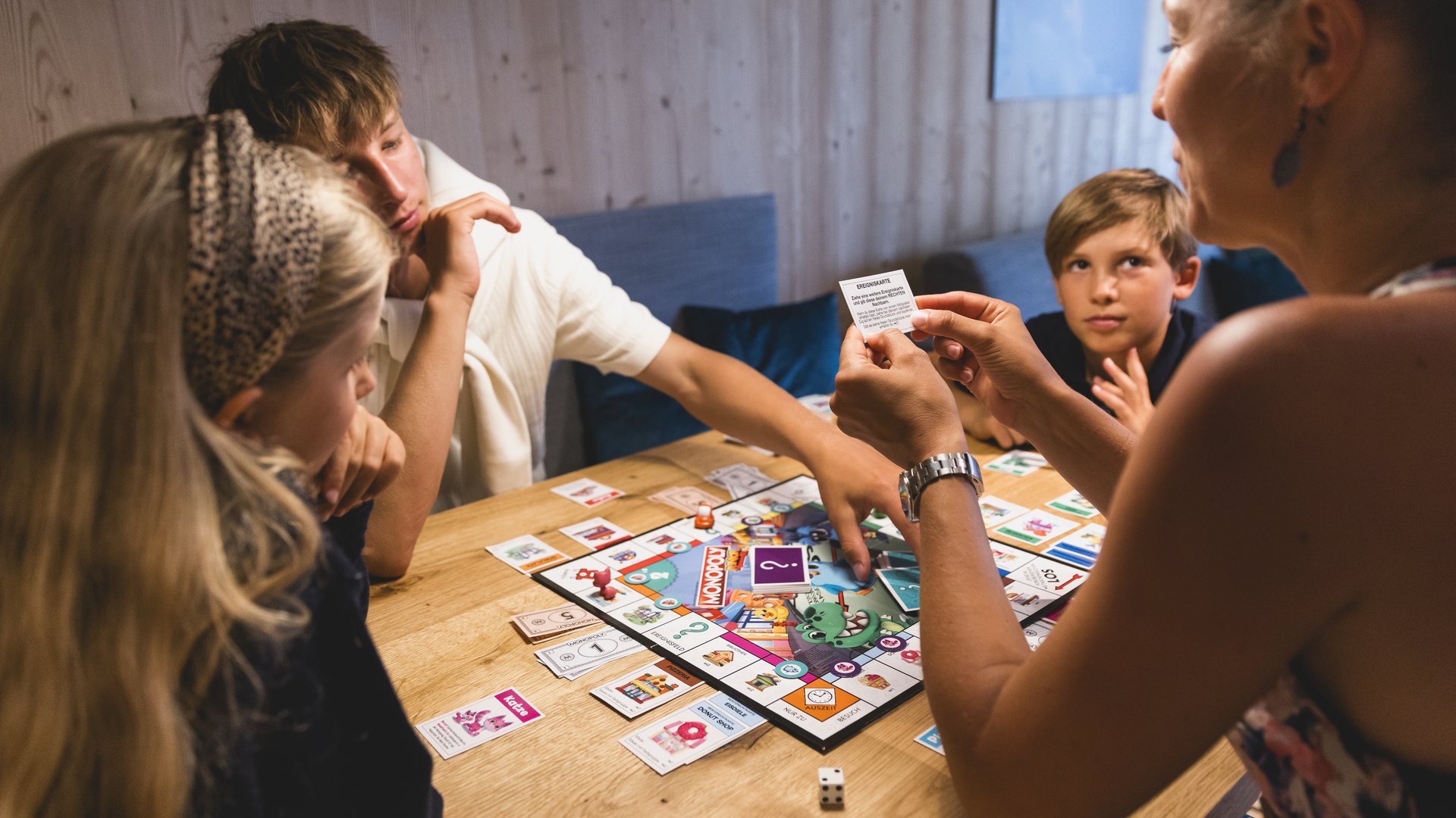 Familie sitzt gemeinsam am Tisch und spielen ein Brettspiel Familie sitzt gemeinsam am Tisch und spielen ein Brettspiel