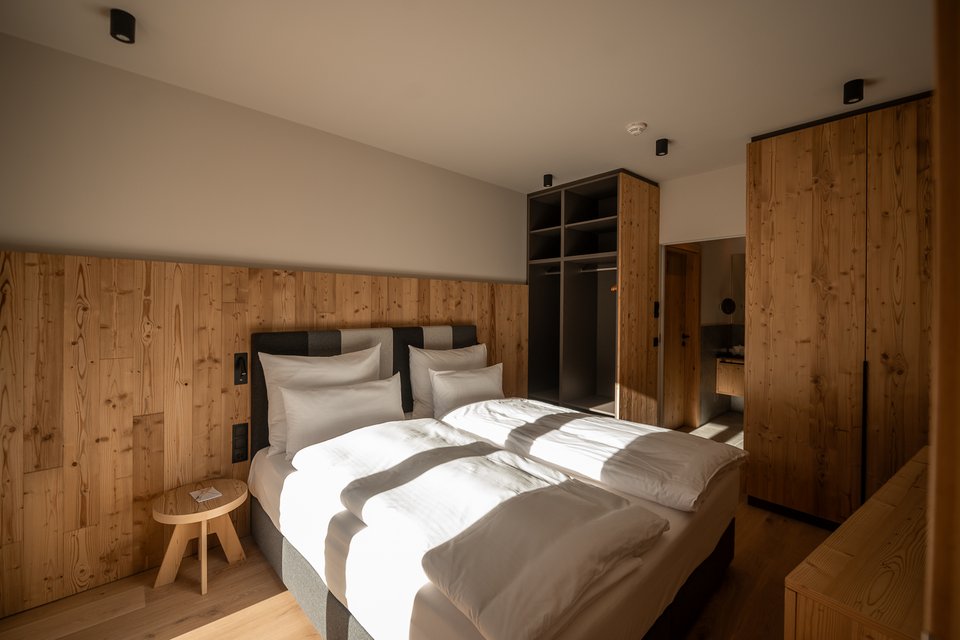 Cross-country skiing in Fieberbrunn: Try it out! Bright bedroom with double bed and wooden furniture in natural light