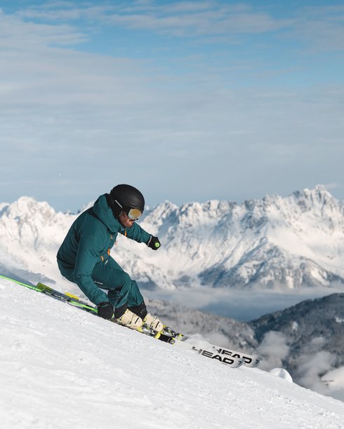 Holiday in Fieberbrunn at the ADEA Lifestyle Suites Skier descending snowy slope with snowy mountains in the background