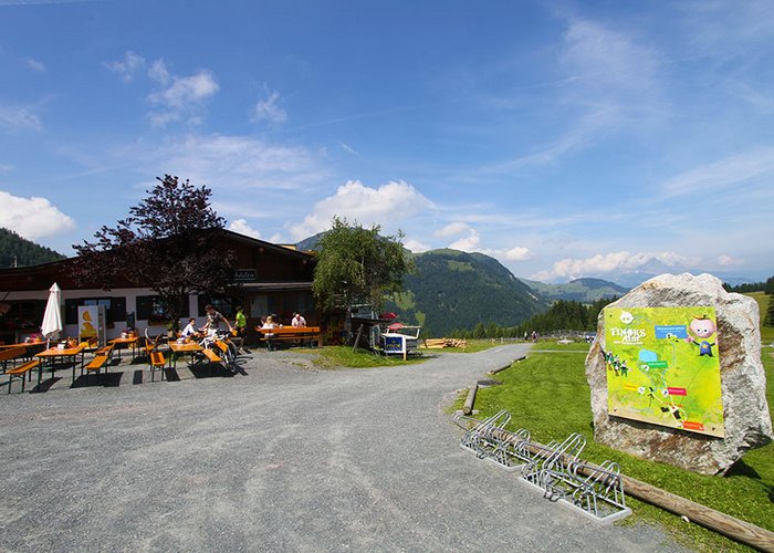 Mountain Hikes in the Kitzbühel Alps Mountain inn with outdoor seating and hiking map on rock in sunny landscape