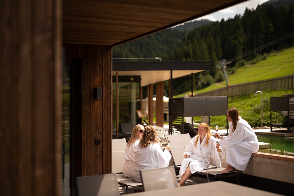 Friends sit together on the terrace in their bathrobes and enjoy a drink. Friends sit together on the terrace in their bathrobes and enjoy a drink.
