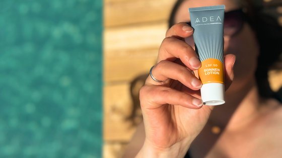 Frau entspannt am Schwimmteich und hält Sonnencreme von den ADEA Lifestyle Suites in der Hand Frau entspannt am Schwimmteich und hält Sonnencreme von den ADEA Lifestyle Suites in der Hand