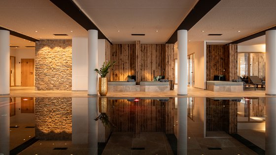 Fieberbrunn: wellness hotel wanted? Modern spa area with stone wall, wood accents, and water reflection