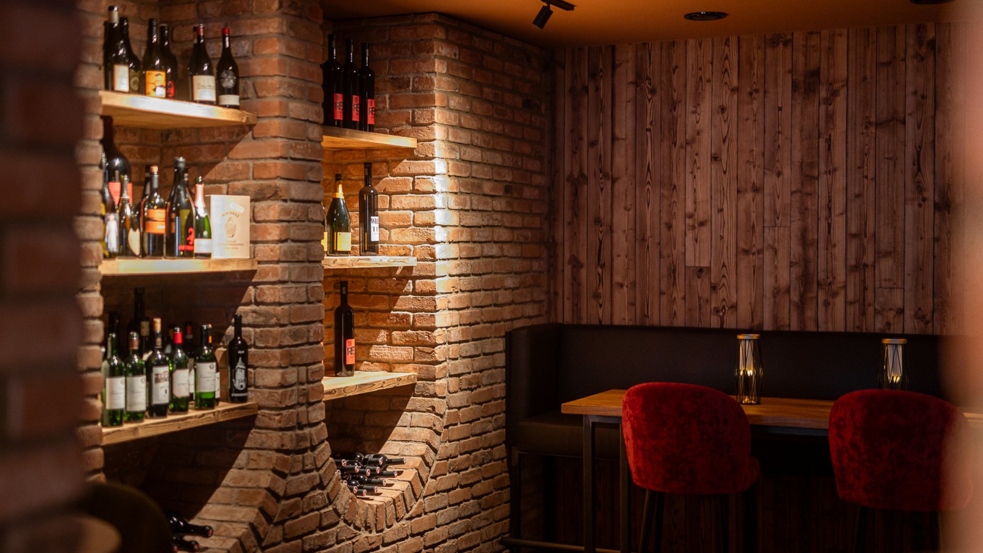 Weinlounge im Restaurant UPSIDEDOWN mit Regalen voller Wein und einer gemütlichen Sitzmöglichkeit Weinlounge im Restaurant UPSIDEDOWN mit Regalen voller Wein und einer gemütlichen Sitzmöglichkeit