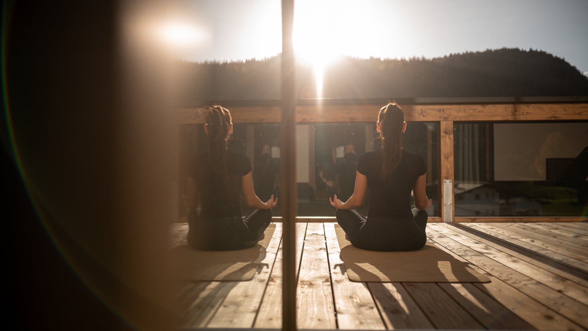 Frau meditiert im Schneidersitz bei Sonnenaufgang auf der Terrasse Frau meditiert im Schneidersitz bei Sonnenaufgang auf der Terrasse