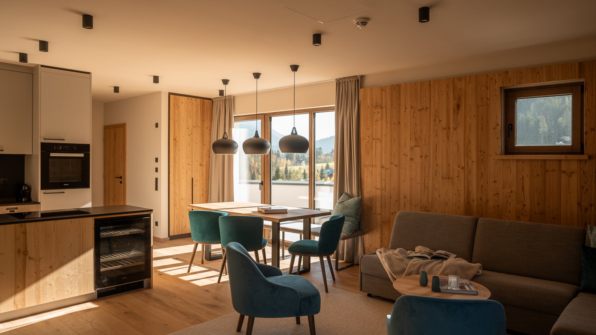 Hotel in Fieberbrunn: ADEA Lifestyle Suites Moderner Wohn- und Küchenbereich mit Holzwänden und türkisen Stühlen