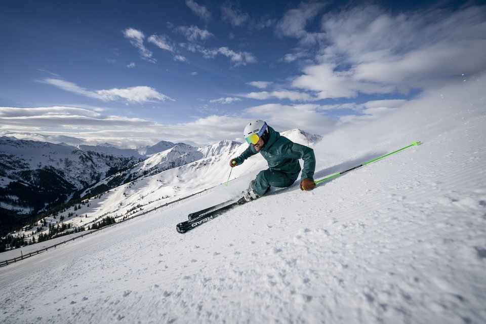 Cross-country skiing in Fieberbrunn: Try it out! Skier skiing fast down snowy mountain slope under a partly cloudy sky