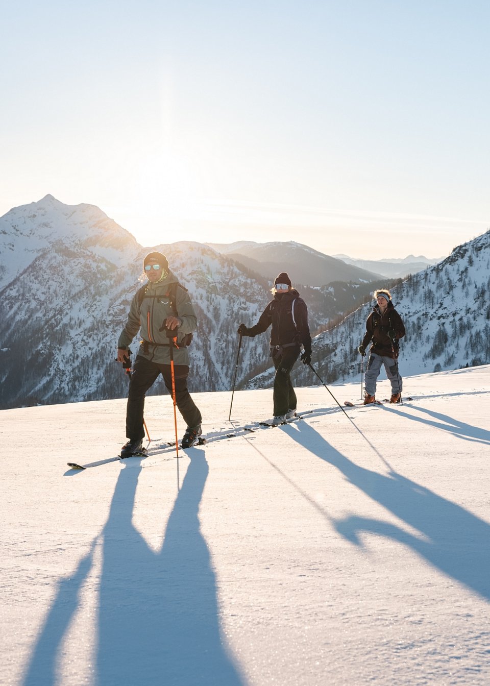 Drei Skitourengeher wandern im Pulverschnee den Berg hinauf Drei Skitourengeher wandern im Pulverschnee den Berg hinauf