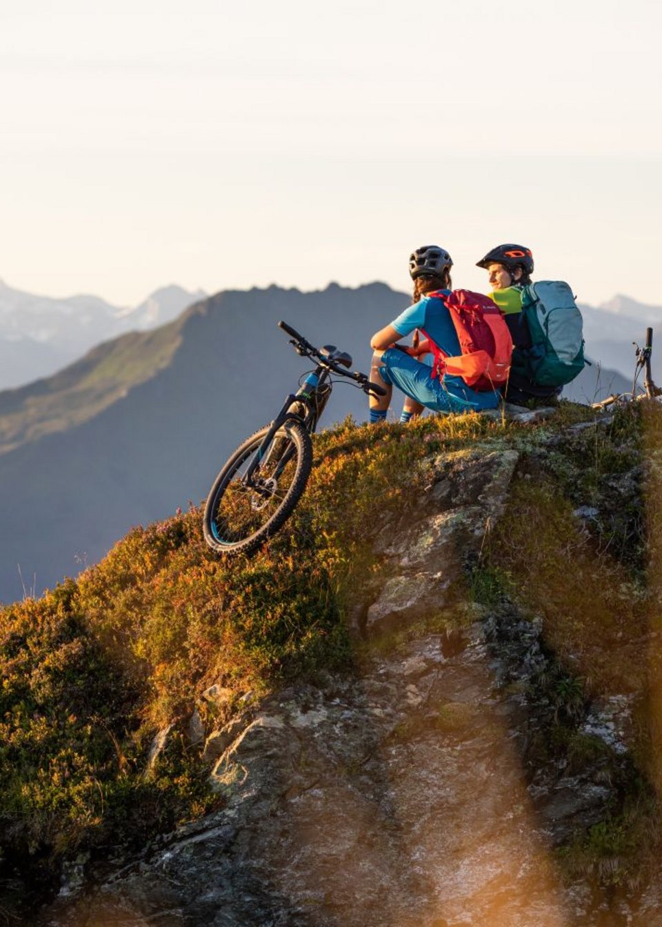 Zwei Mountainbiker sitzen auf einem Berggipfel in den Kitzbüheler Alpen Zwei Mountainbiker sitzen auf einem Berggipfel in den Kitzbüheler Alpen