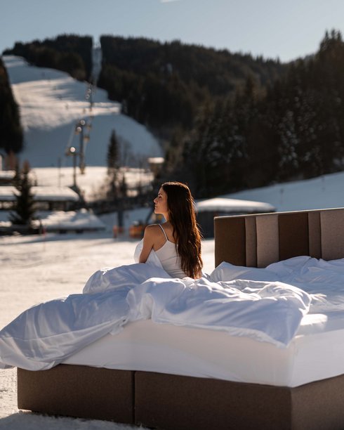 Woman sitting on the bed in the middle of the ski slope Woman sitting on the bed in the middle of the ski slope
