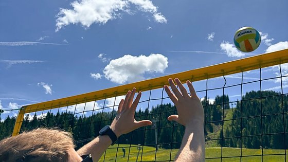 Urlaub für... Person spielt Volleyball im Freien unter blauem Himmel mit Volleyballnetz