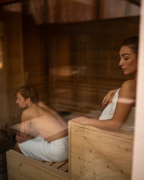Urlaub für... Mann und Frau entspannen in Sauna, beide in Handtüchern, nachdenklich