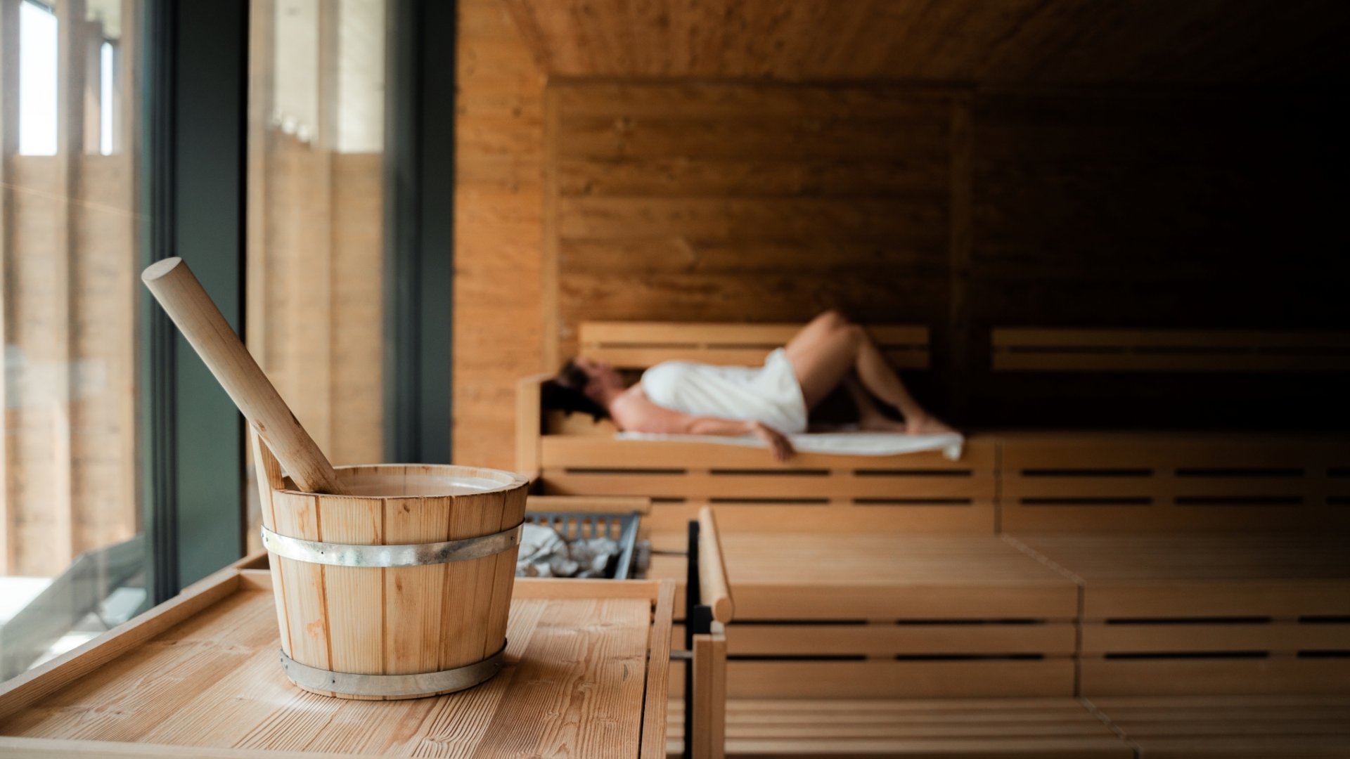 Hotel in Fieberbrunn: ADEA Lifestyle Suites Saunabucket und Frau in weißem Handtuch in Sauna entspannend