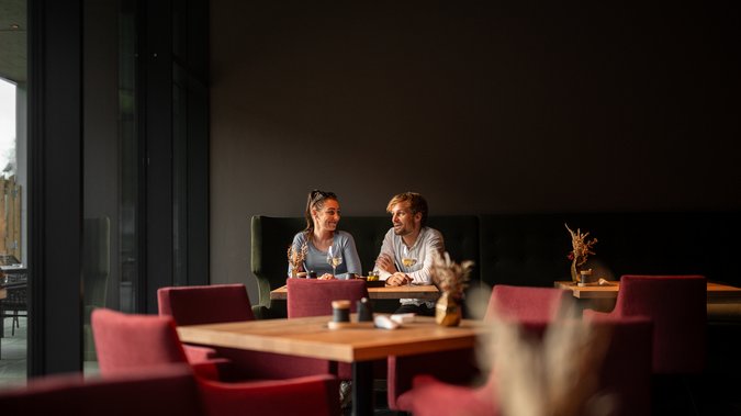 ADEA: dein Hotel mit Fitnessstudio in Österreich Paar sitzt in einem Restaurant und unterhält sich bei Wein.