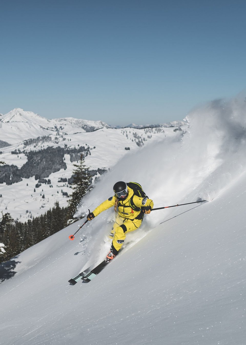 Kurzurlaub in Tirol: Wellness-Auszeit im ADEA Fieberbrunn Skifahrer in gelber Kleidung fährt schnell einen schneebedeckten Hang hinab
