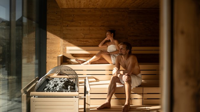 ADEA Lifestyle Suites: dein Hotel mit Sauna im Zimmer in Tirol Mann und Frau entspannt in moderner Sauna mit Holzwänden und Ofen