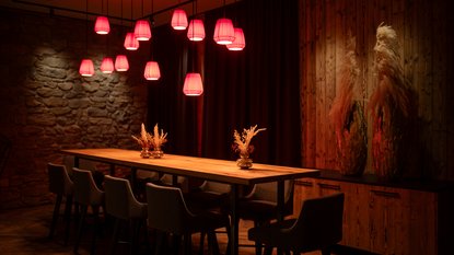 Long dining table with high chairs and red lamps in the lobby lounge in Fieberbrunn Long dining table with high chairs and red lamps in the lobby lounge in Fieberbrunn