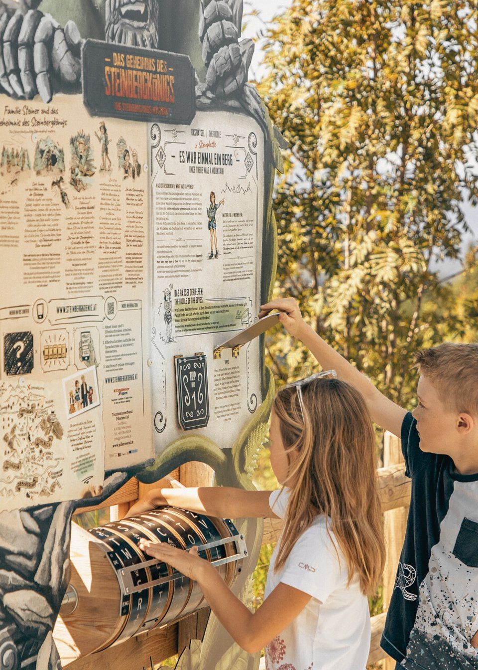Kinder versuchen das Rätsel des Steinbergkönigs zu lösen an einem großen Aufsteller Kinder versuchen das Rätsel des Steinbergkönigs zu lösen an einem großen Aufsteller
