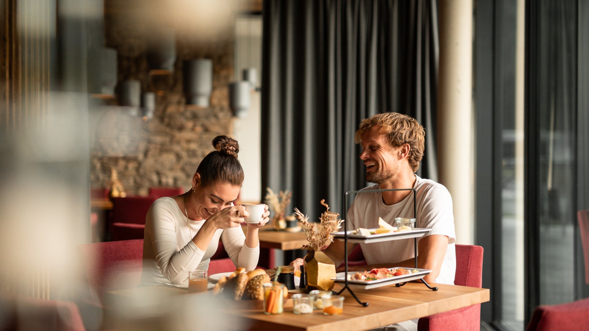 Paar lacht beim Frühstück im Restaurant UPSIDEDOWN in Fieberbrunn Paar lacht beim Frühstück im Restaurant UPSIDEDOWN in Fieberbrunn