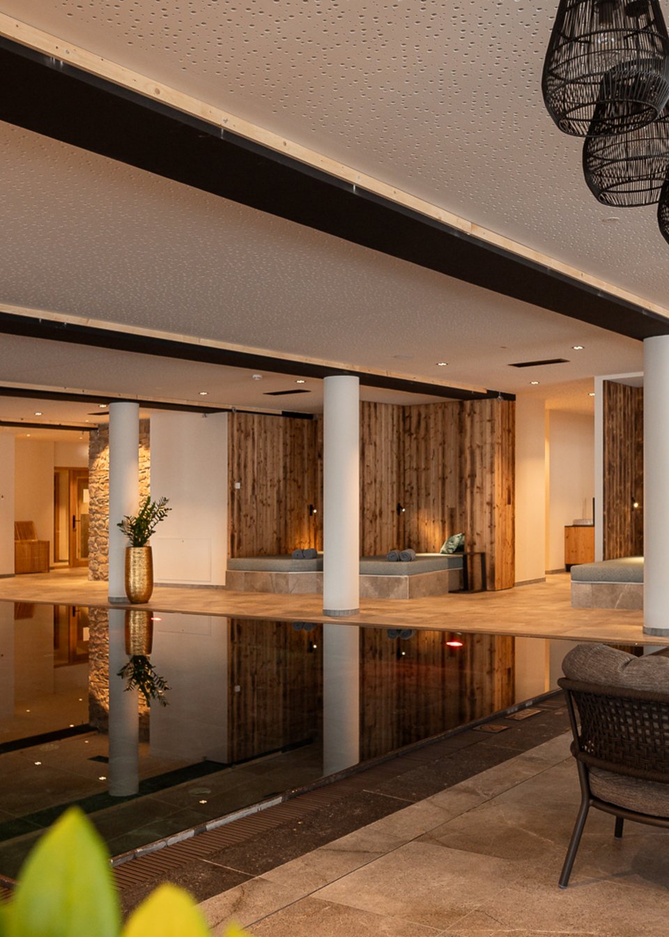 Hotel in Fieberbrunn: ADEA Lifestyle Suites Moderner Innenpoolbereich mit Sitzgelegenheiten und warmem Licht