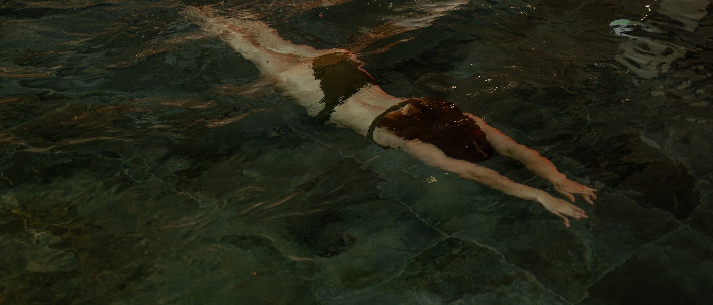 Day Spa inmitten der Kitzbüheler Alpen Frau schwimmt unter Wasser mit gestreckten Armen