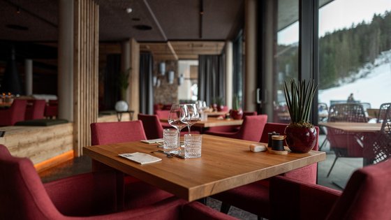 Hotel in Fieberbrunn: ADEA Lifestyle Suites Modernes Restaurant mit Holztischen, roten Stühlen und Bergblick