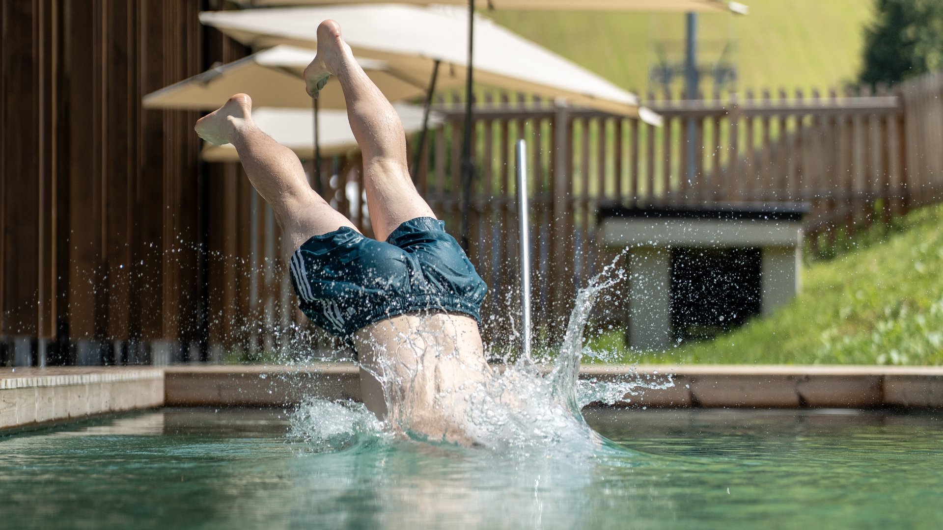 Fieberbrunn: wellness hotel wanted? Person diving headfirst into a pool with grassy hillside in background