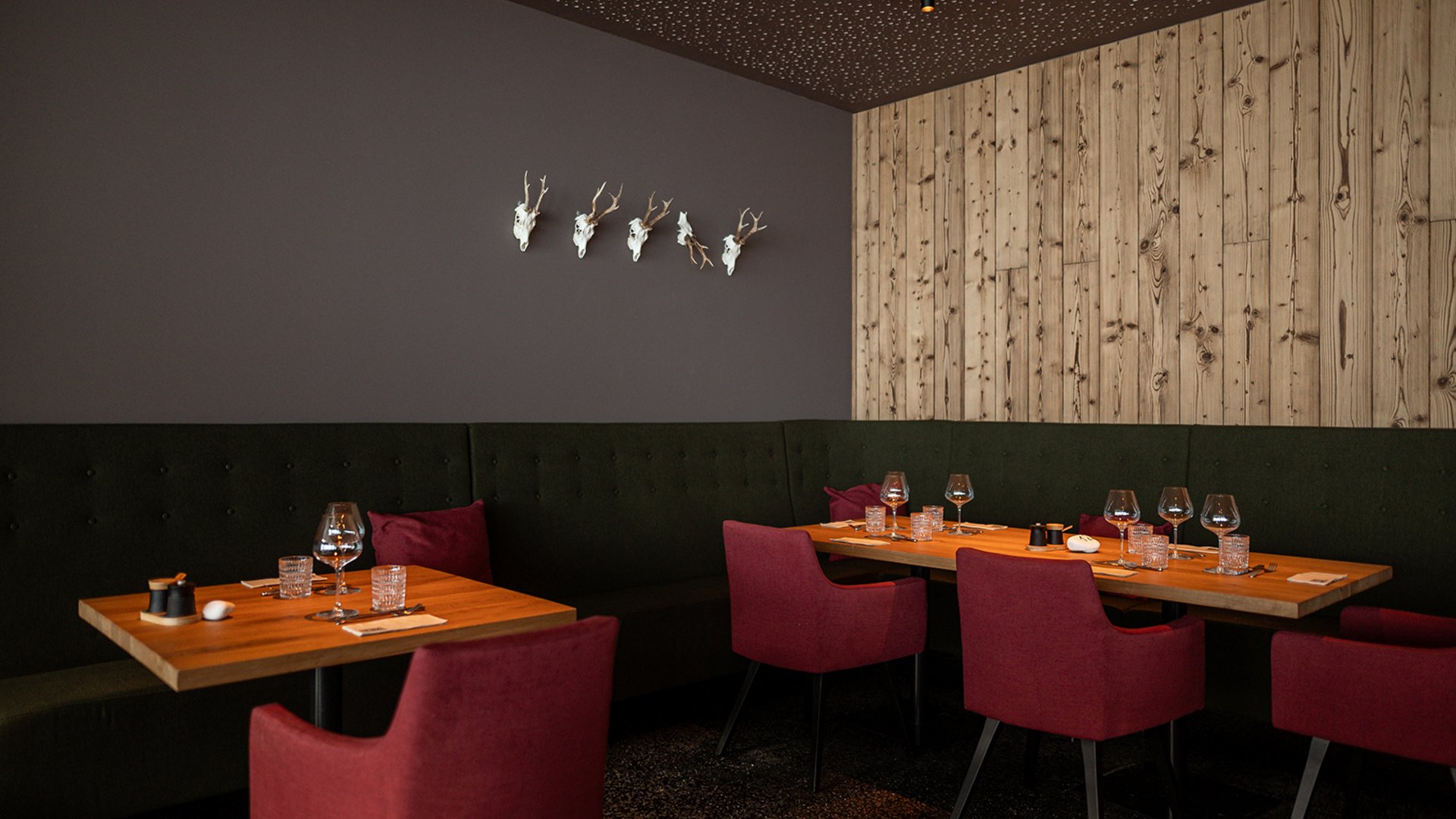 Sitzmöglichkeiten mit gedeckten Tischen und roten Stühlen im Restaurant UPSIDEDOWN in Fieberbrunn Sitzmöglichkeiten mit gedeckten Tischen und roten Stühlen im Restaurant UPSIDEDOWN in Fieberbrunn