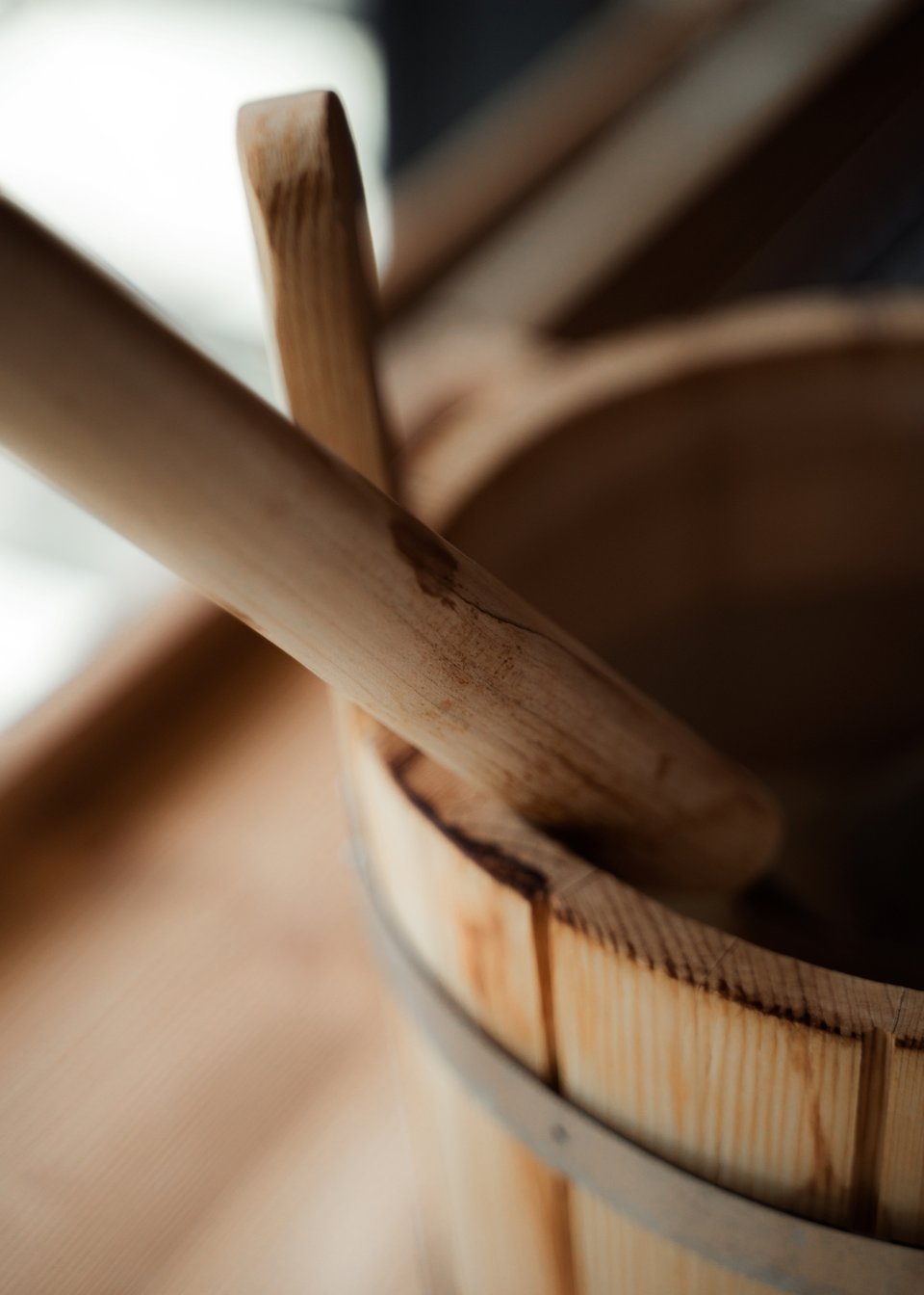 Day Spa inmitten der Kitzbüheler Alpen Nahaufnahme eines Holzbuckets mit Schöpflöffel auf einer Holzbank