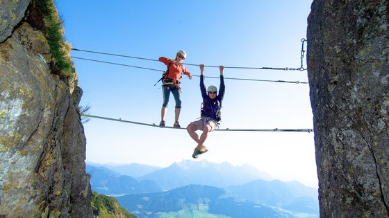 Kurzurlaub in Tirol: Wellness-Auszeit im ADEA Fieberbrunn Zwei Kletterer auf Drahtseilbrücke zwischen Felsen mit Bergpanorama